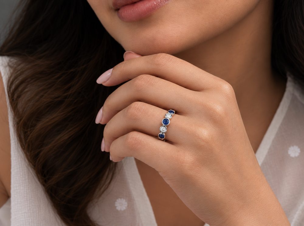 Hand wearing a blue sapphire and diamond ring