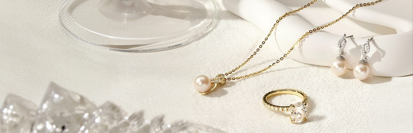 Pearl necklace, diamond earrings, and a gold ring on linen